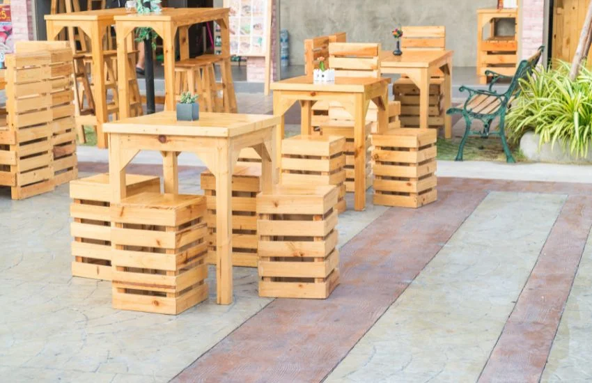 Zona chill out con palets reciclados, con mesas y taburetes de madera en un espacio exterior acogedor y decorativo.