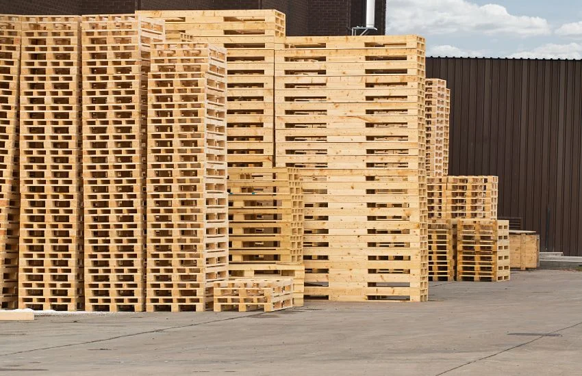 Palets de madera apilados en almacén exterior, listos para barnizar un palet paso a paso y prepararlo para uso decorativo o funcional.
